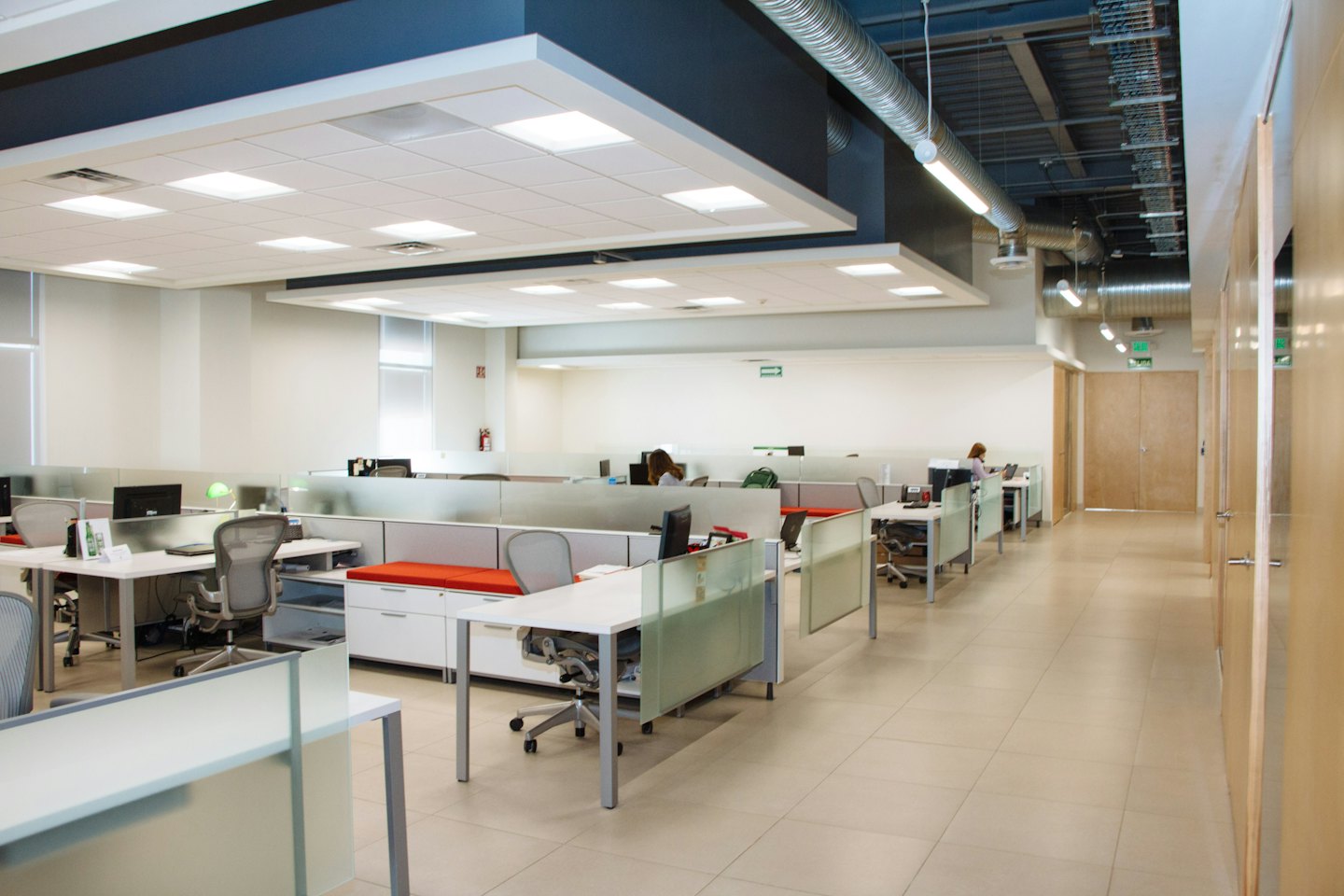 Jasne biuro typu open space z boksami i pracującymi pracownikami.